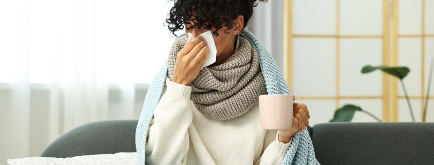 Cold symptom. Young woman with tissue and cup of hot drink at home